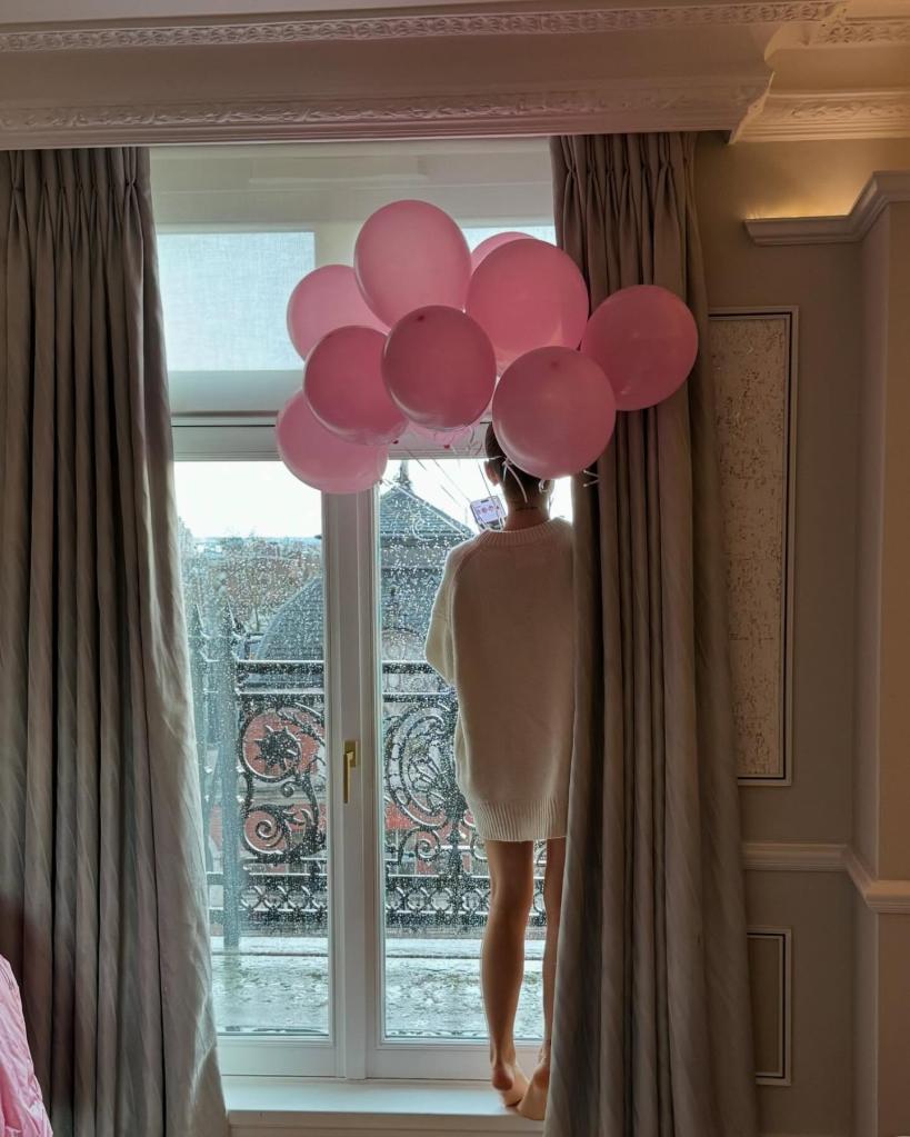 Ariana Grande holding pink balloons near a balcony